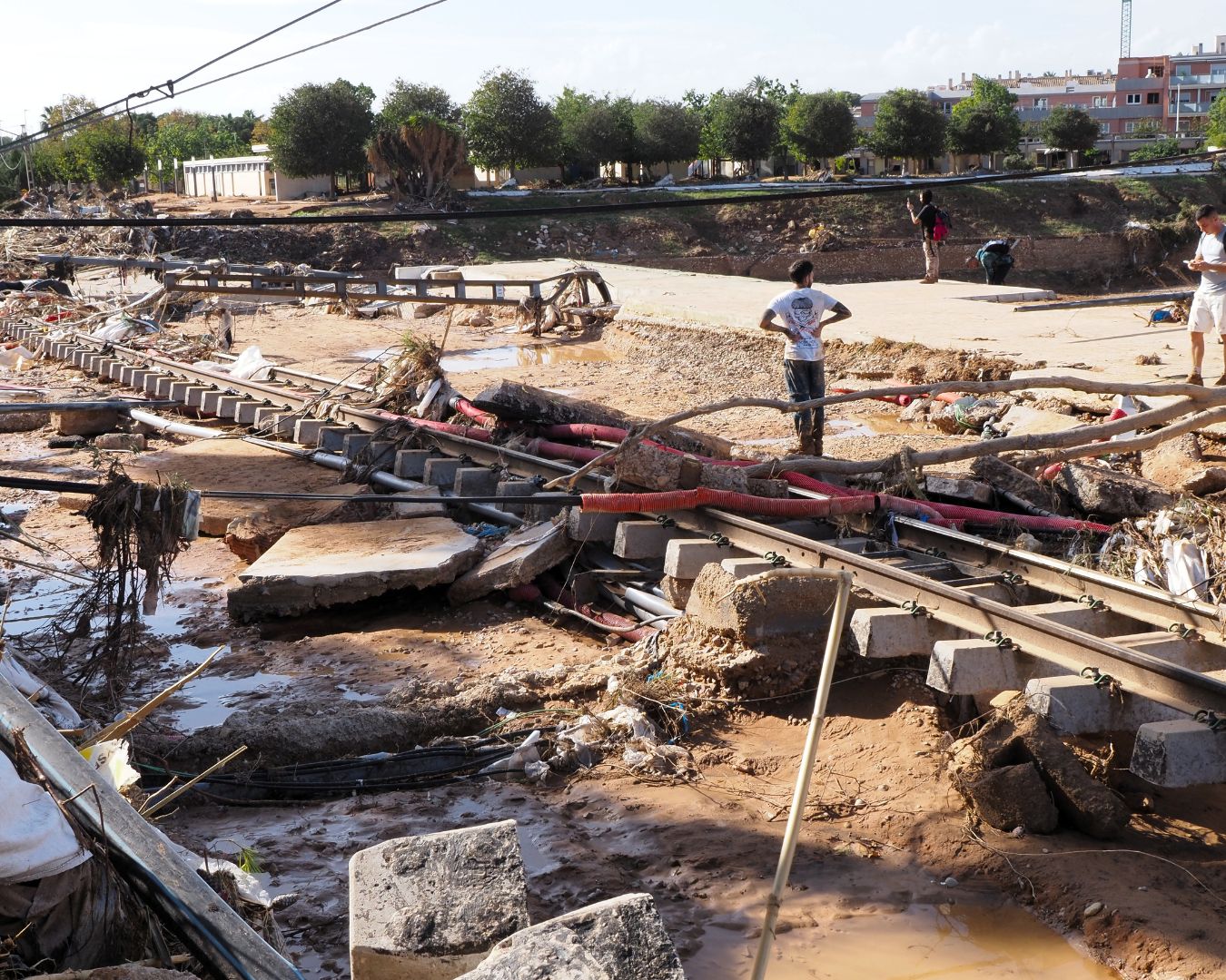 Zona industrial devastada por la DANA, con vías dañadas, escombros, cables caídos y barro acumulado.